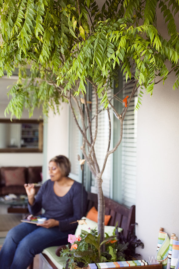 Indira sitting underneath the fragrance curry leaf tree enjoying her freshly made pesto with some crackers